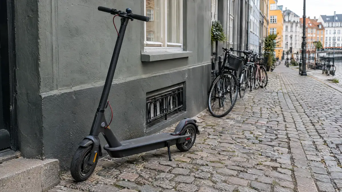 Privat elløbehjul stillet op ad en mur på en brostensbelagt gade i København